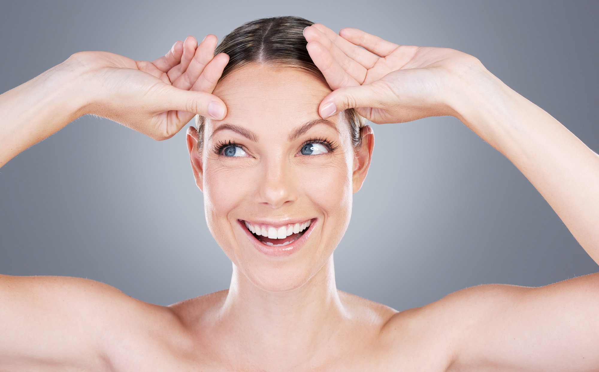 Studio shot of an attractive mature woman touching her forehead against a grey background